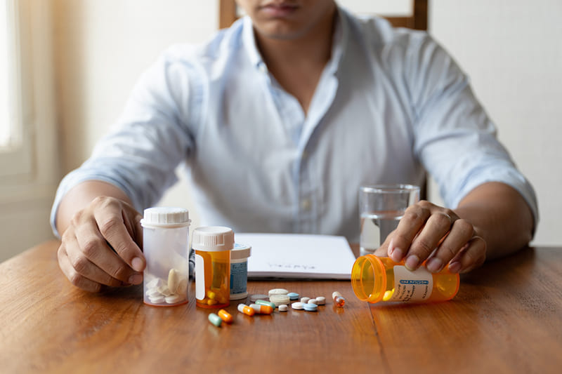 Человек рассматривает лекарства на столе